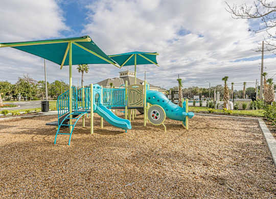 A playground with a blue slide and a green canopy.