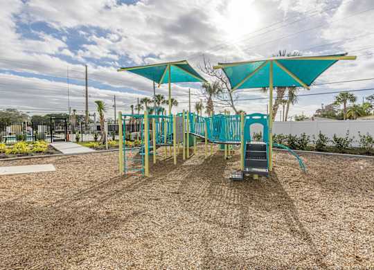A playground with a blue canopy and a slide.