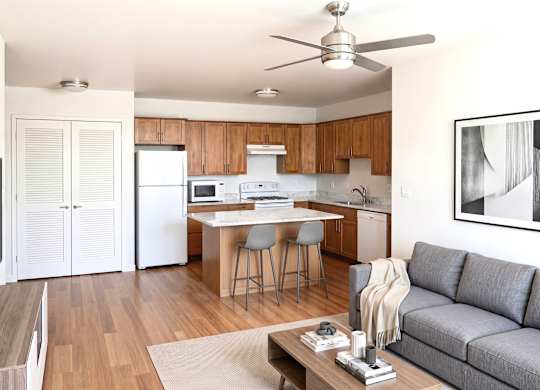 A modern kitchen with a dining table and a grey sofa.