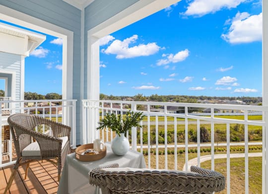 a balcony with two chairs and a table and a view of the water  at Osprey Park 62+ Apartments & Cottages, Kissimmee, FL, 34758