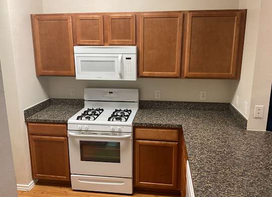 an empty kitchen with white appliances and wooden cabinets