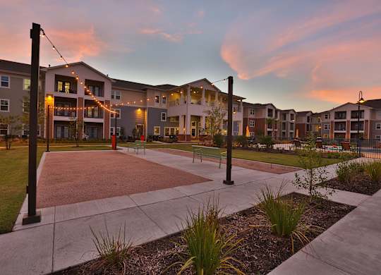 an exterior view of an apartment complex at sunset with a courtyard