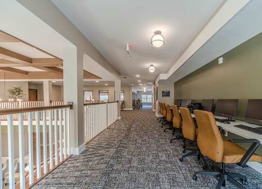A long hallway with rows of chairs and computers on the side.