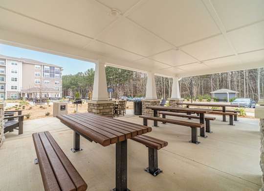 A covered outdoor seating area with benches and tables.