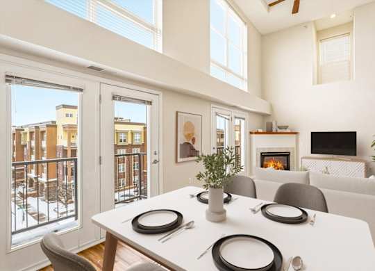 A dining table with four place settings is in the middle of a living room.