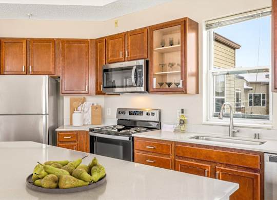 A kitchen with a refrigerator, microwave, oven, and sink.