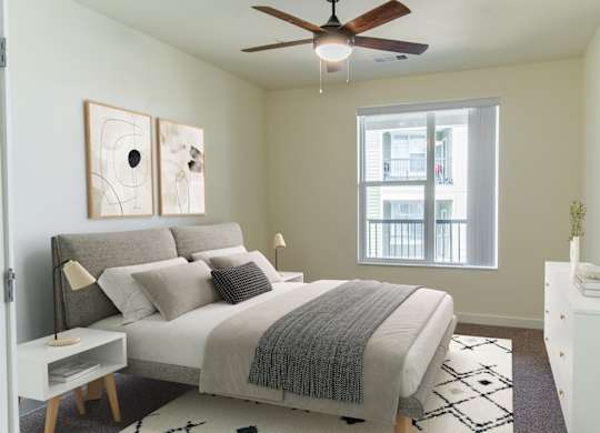 A bedroom with a bed, nightstand, and a ceiling fan.