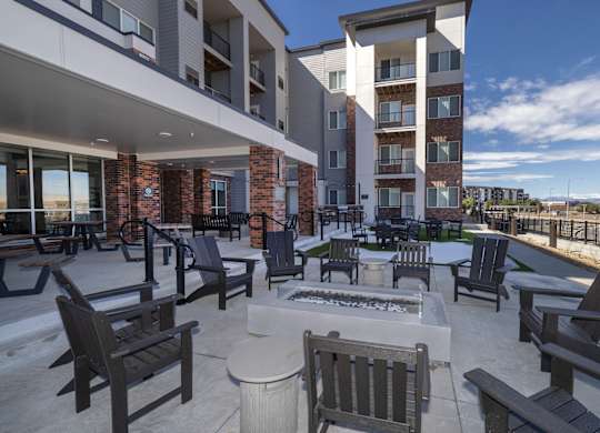 A patio with chairs and a table with a fire pit in the middle.