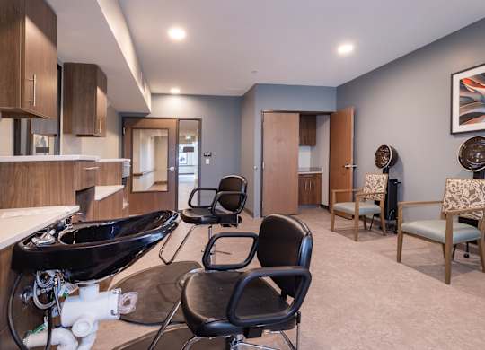 A bathroom with a black sink and two chairs.