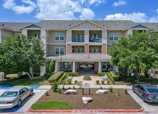 a large building with cars parked in front of it at Mariposa at Bay Colony, Dickinson, TX