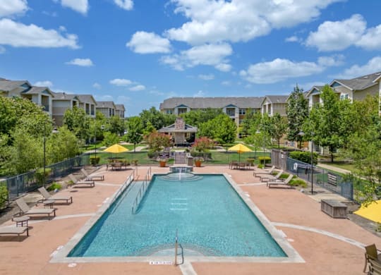 a pool with lounge chairs and umbrellas at the resort on a sunny day at Mariposa at Bay Colony, Dickinson, 77539