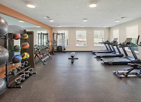 A gym with a variety of equipment including treadmills, weights, and exercise machines.