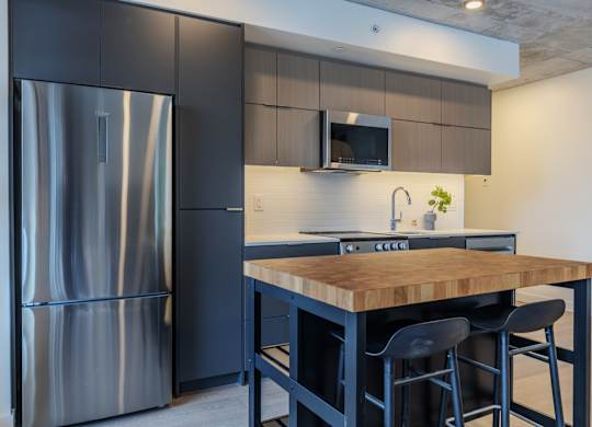 A modern kitchen with a wooden island and stainless steel appliances.