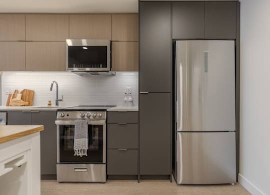 A modern kitchen with a stainless steel refrigerator and oven.