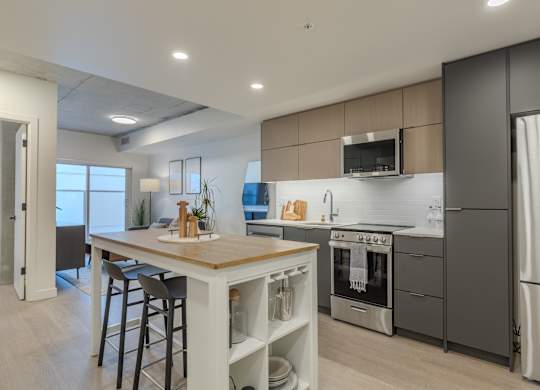 A modern kitchen with a wooden island and stainless steel appliances.