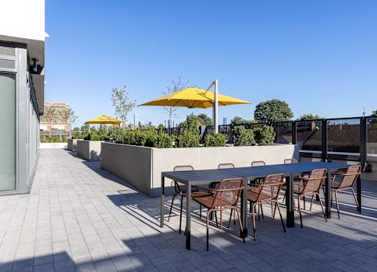 A patio with a table and chairs and umbrellas.