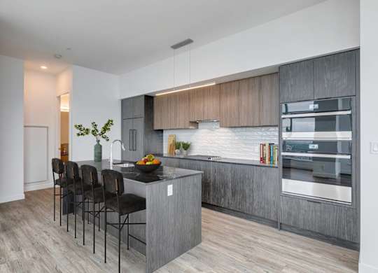 A modern kitchen with a large island and chairs.