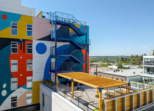 A colorful building with a balcony and a view of the city.