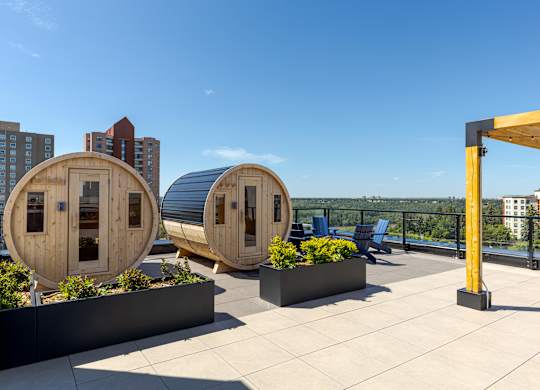 Two round wooden pods with windows are on a rooftop with a cityscape in the background.