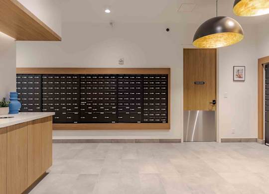 A modern office lobby with a reception desk and a wall of black chairs.