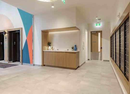 A hallway with a reception desk and a green exit sign.