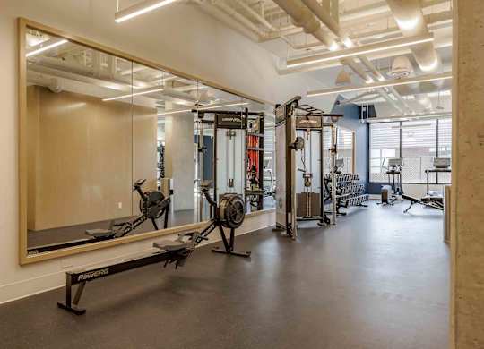 A gym with a mirror, weights, and exercise equipment.