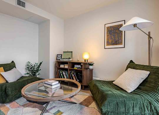 A living room with a green couch, a coffee table, and a lamp.