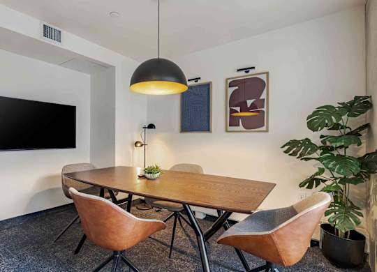 A conference room with a table, chairs, and a television.
