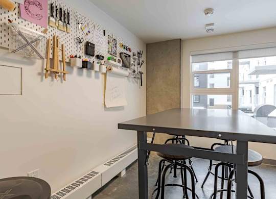 A kitchen with a table and chairs and a wall of utensils.