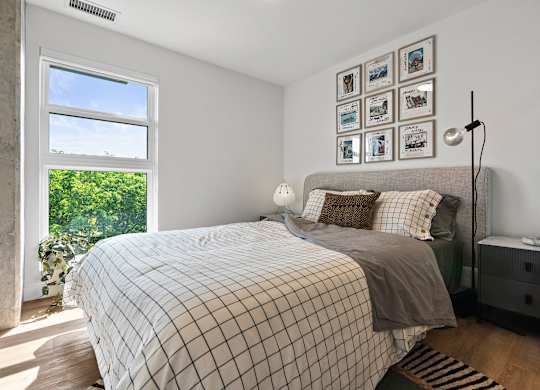 A bedroom with a large bed and a window overlooking a green landscape.