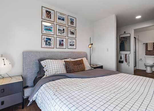 A bedroom with a bed, nightstand, and pictures on the wall.