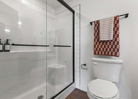 A white toilet sits next to a glass shower stall.
