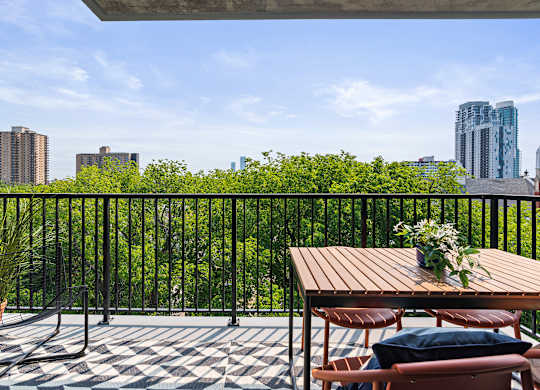 A balcony with a table and chairs overlooking a cityscape.