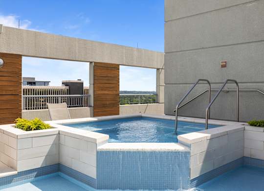 A small pool with a waterfall feature in the middle of it at Clayton on the Park Apartments, Missouri