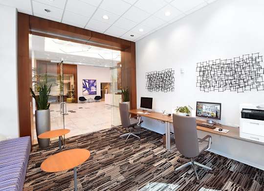 A modern office with a purple sofa and a wooden desk.