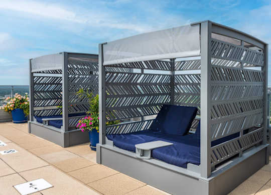 Two beds with blue pillows and grey striped headboards.