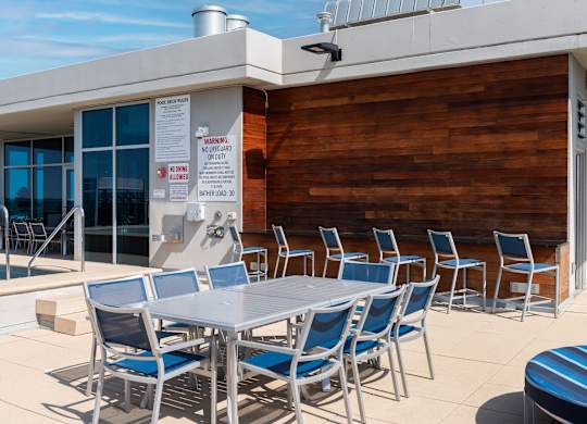 A poolside table with chairs and a warning sign on the wall.
