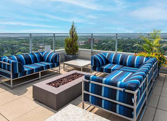 A patio with blue and white striped couches and a fire pit.