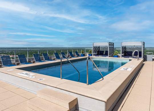 A large outdoor swimming pool with lounge chairs and a view of the horizon.