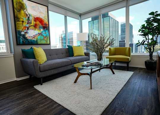 A living room with a grey couch and yellow pillows.