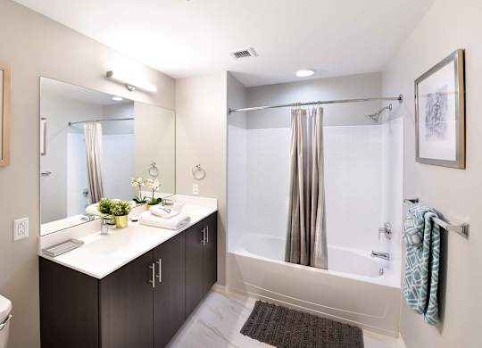 A bathroom with a white counter top and a shower with a glass door.