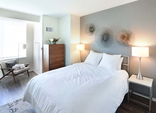 A bedroom with a large bed and a chair by the window.
