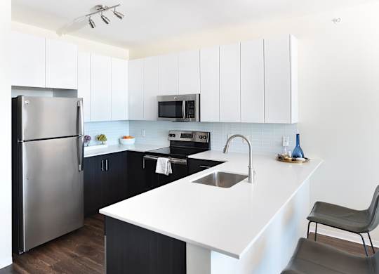 A modern kitchen with a white countertop and black cabinets.