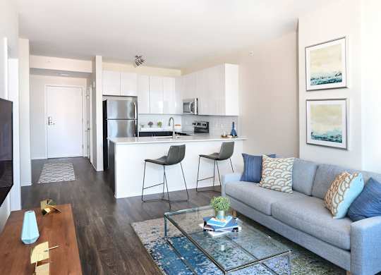 A modern living room with a grey couch and a glass coffee table.