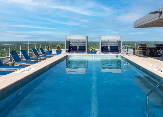 A large outdoor swimming pool with lounge chairs and a view of the horizon.