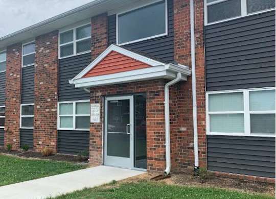 a brick apartment building with a front door and grass