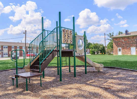 a playground with a slide and stairs in front of a building