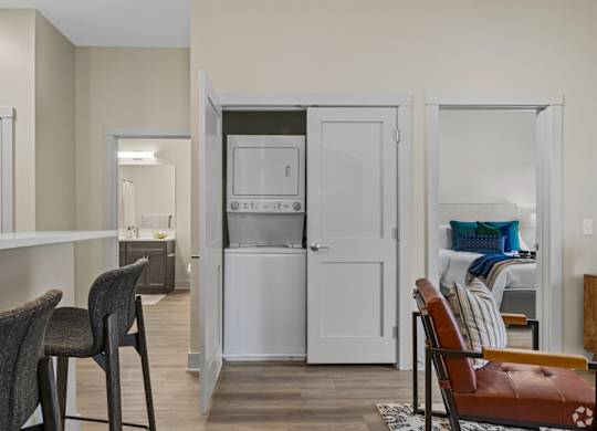 A kitchen area with a refrigerator, microwave, and a dining table with chairs.