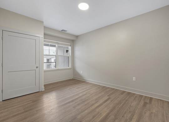 A room with a white door and wooden flooring.