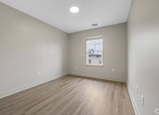 A room with a window and wooden flooring.